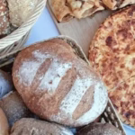 Mesa de mercado con panes artesanales, bollos y dulces caseros de El Epicúreo en la Axarquía