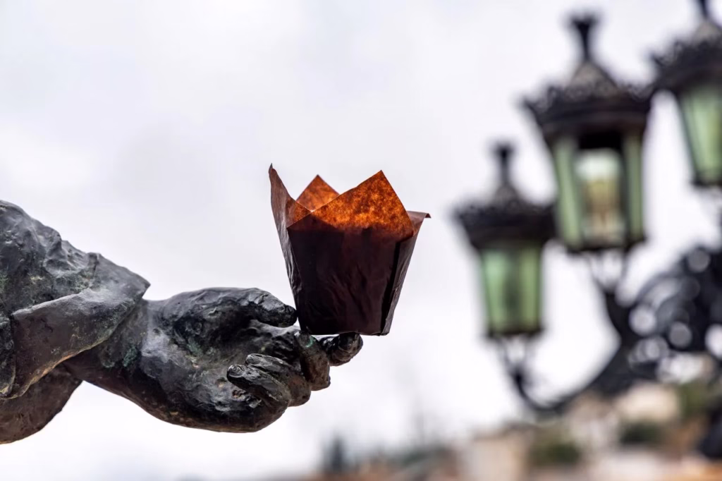 Fotografía creativa de Matthias Winter mostrando un muffin sobre la mano de una estatua de bronce en Cómpeta.