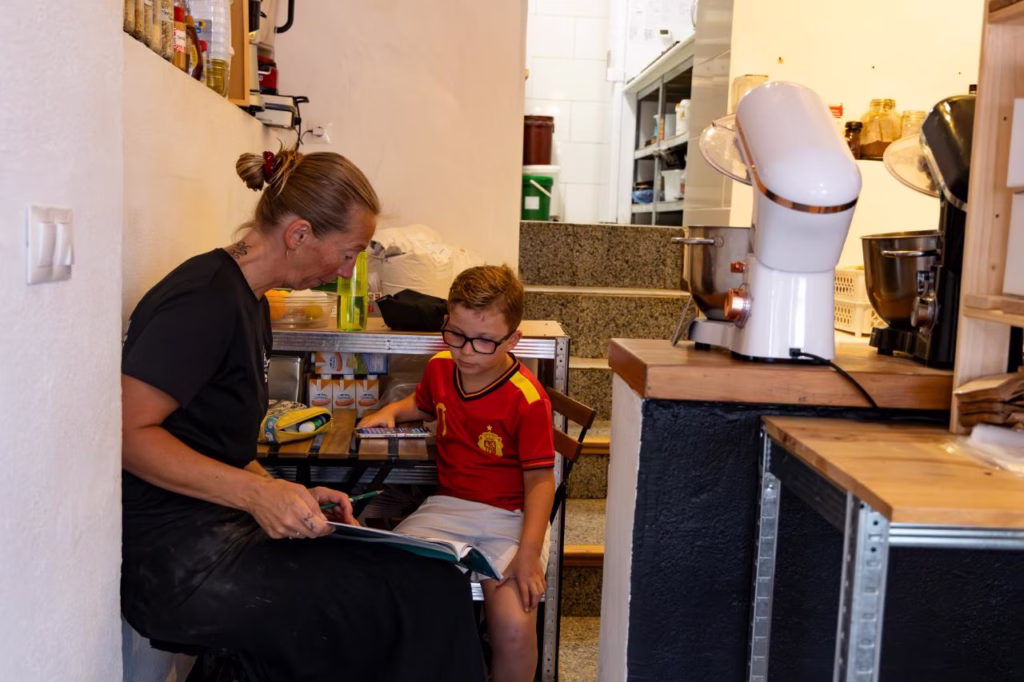 Madre e hijo haciendo los deberes escolares en el interior de la panadería artesanal El Epicúreo en Cómpeta.