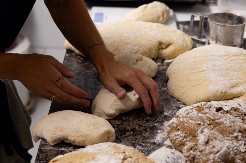 Panadera amasando a mano diferentes tipos de masa de pan artesanal en el obrador de El Epicúreo en Cómpeta