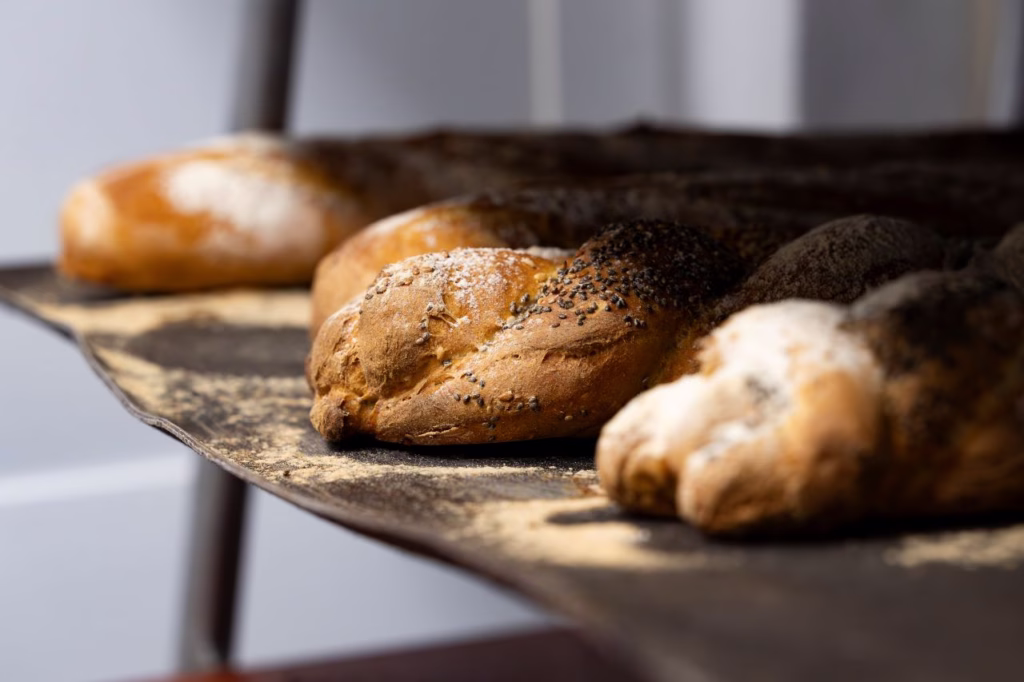 Panes artesanales y trenzas con semillas recién horneados sobre bandeja de la panadería El Epicúreo en Cómpeta.